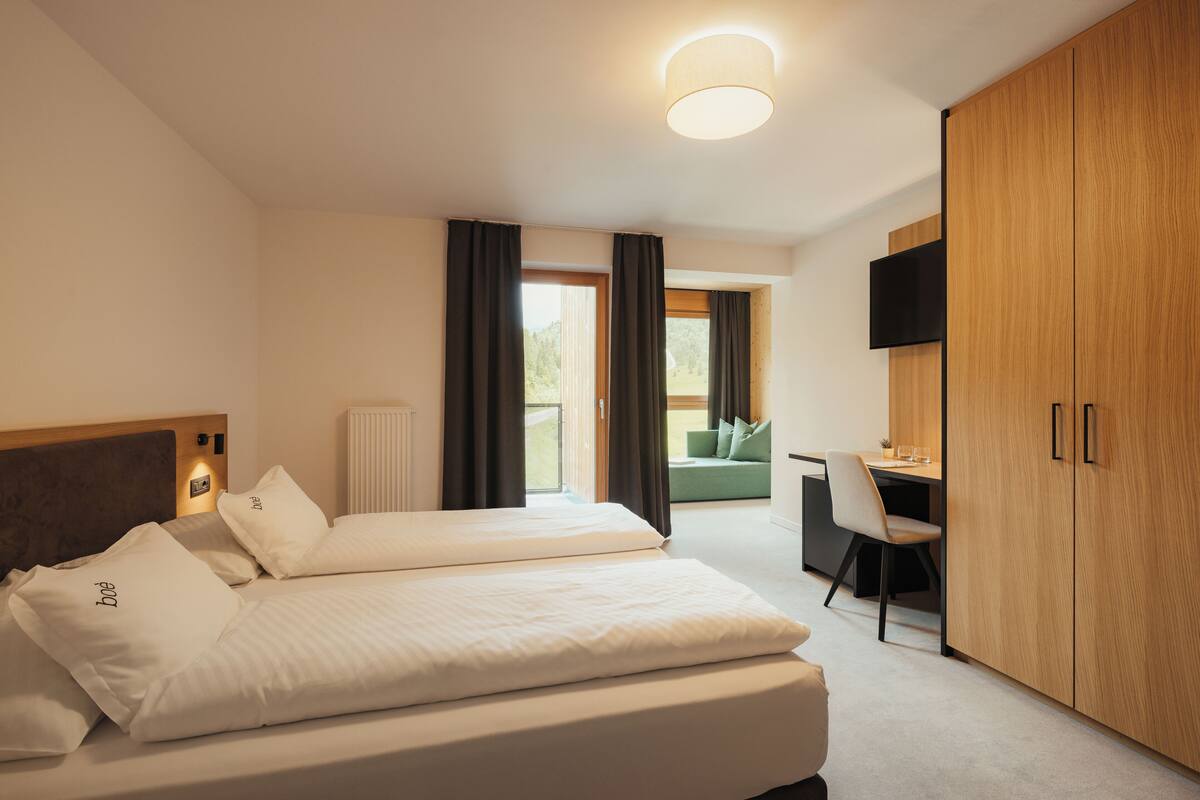 Hotellihuone, jossa on kaksi sänkyä, työpöytä, tuoli, televisio ja vaatekaappi.