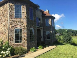 A stone house with a large front porch, multiple windows, and a well-maintained lawn. - Sugarland Farmhouse (Morgantown)