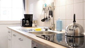 Una cocina moderna con un lavamanos de acero inoxidable, una cafetera y diversos utensilios.