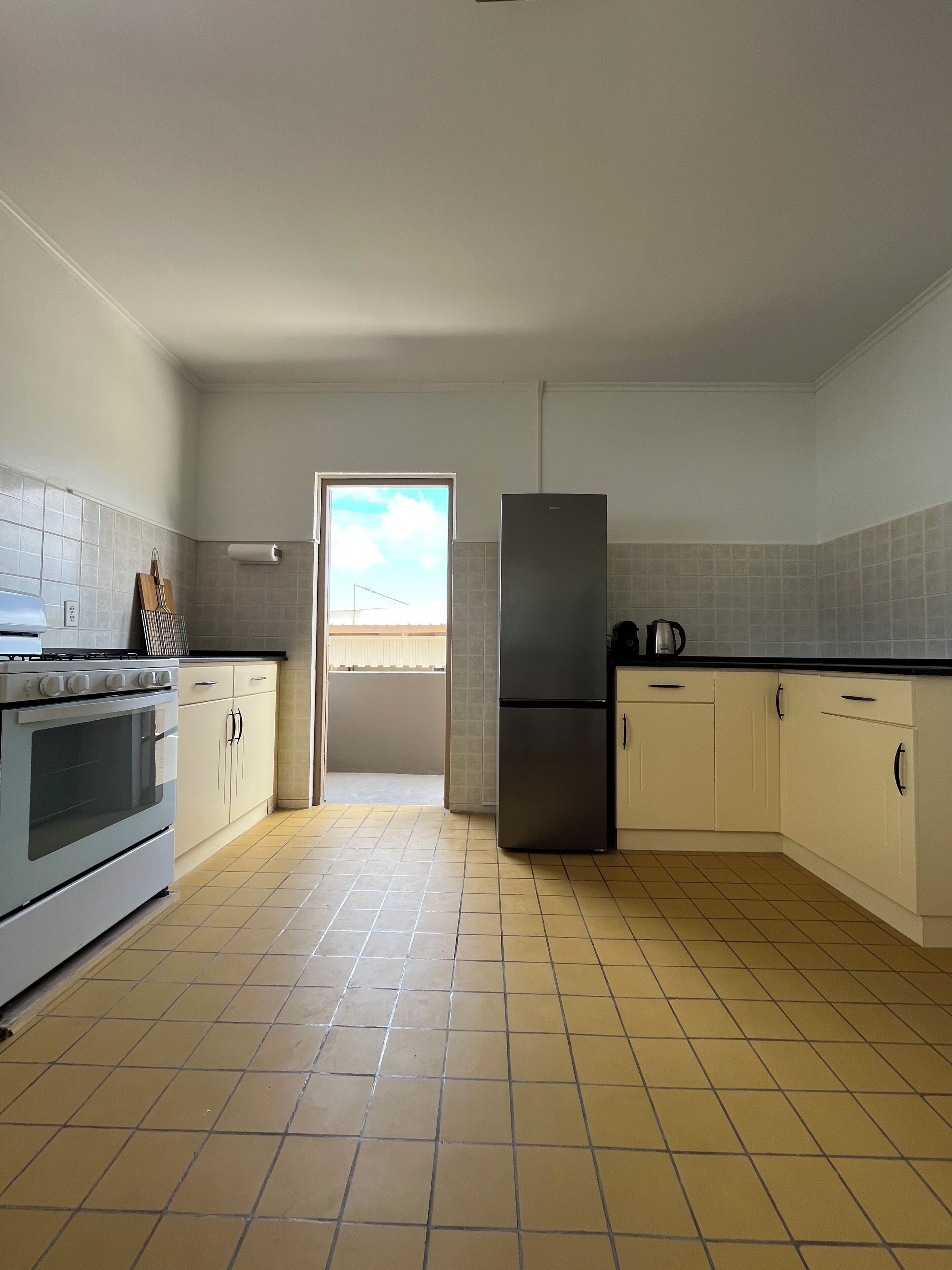 A kitchen with a stove, oven, refrigerator, and cabinets.