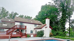 Ein Wohngebiet-Schwimmbad mit roter Poolumrandung, einer Holztreppe und einem Haus im Hintergrund.