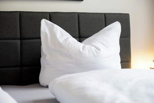 A bed with white bedding and a dark headboard.