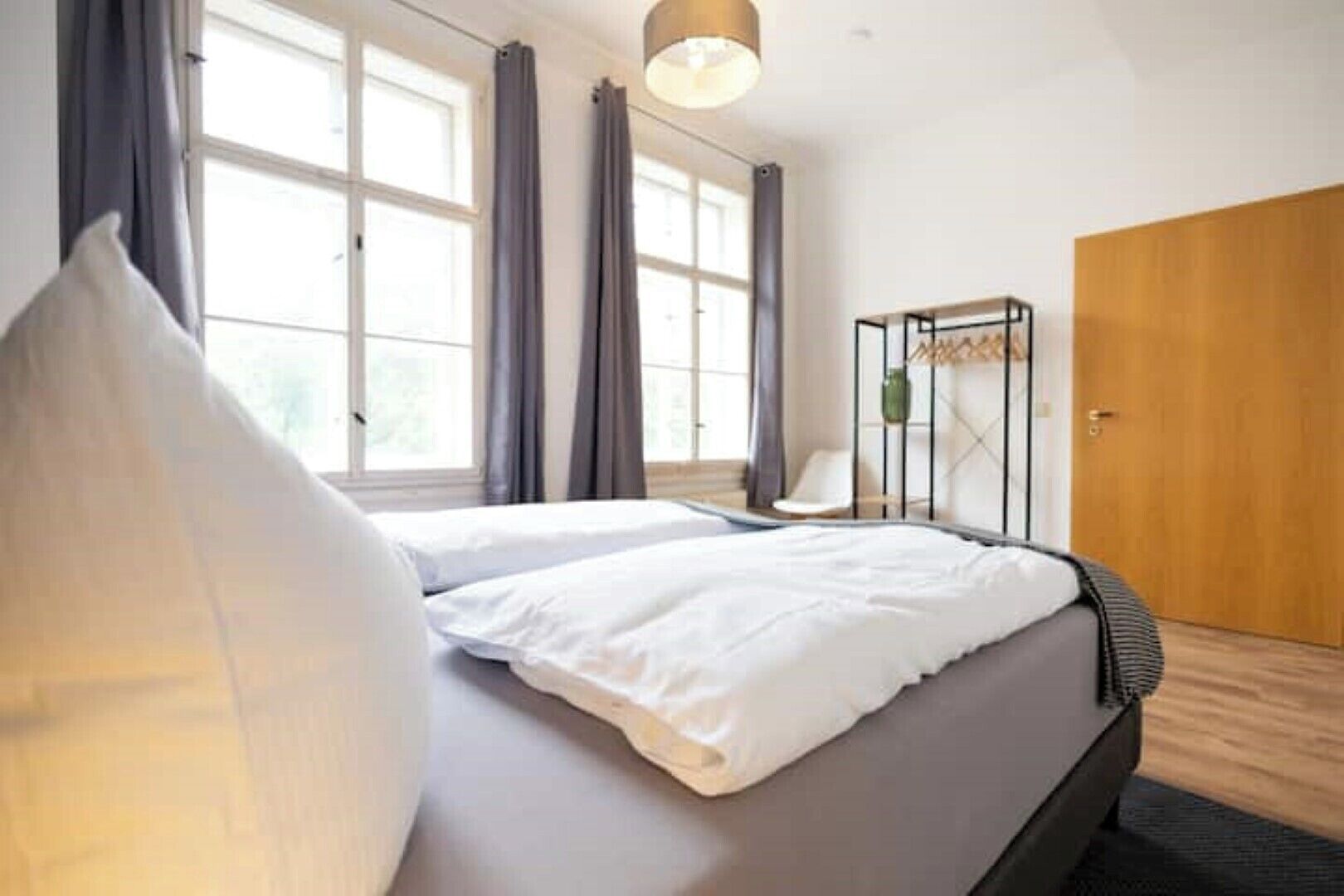 Ein modernes Schlafzimmer mit einem großen Bett, einem Holzschrank und einem Fenster mit Vorhängen.