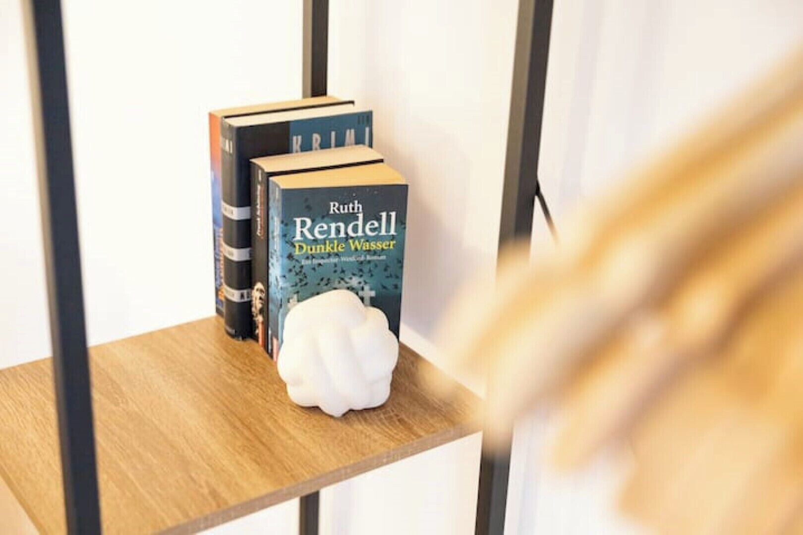 A bookshelf with books and a white decorative object.