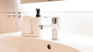 A bathroom sink with a modern faucet and a soap dispenser.
