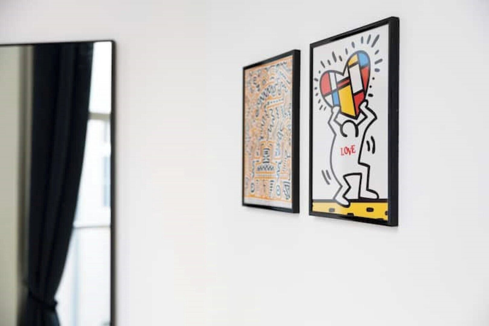 Twee ingelijste kunstwerken aan een witte muur.