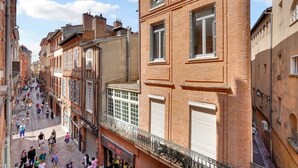 Une rue étroite bordée de bâtiments historiques, avec des balcons et des devantures de magasins.
