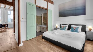 Une chambre avec un grand lit, une salle de bain et un coin repas.