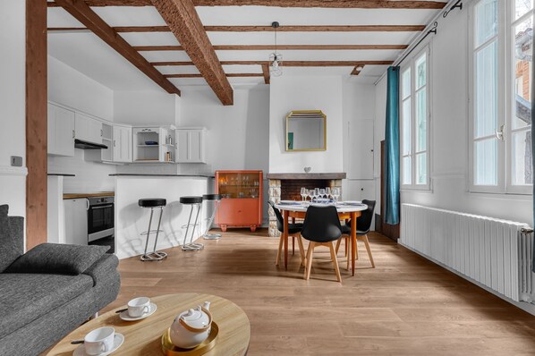 Une cuisine moderne avec des armoires blanches, un plafond en bois et un coin repas avec une table dressée pour quatre personnes.