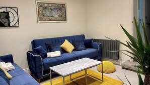 Una sala moderna con un sofá azul, una mesa de centro blanca y una alfombra amarilla.