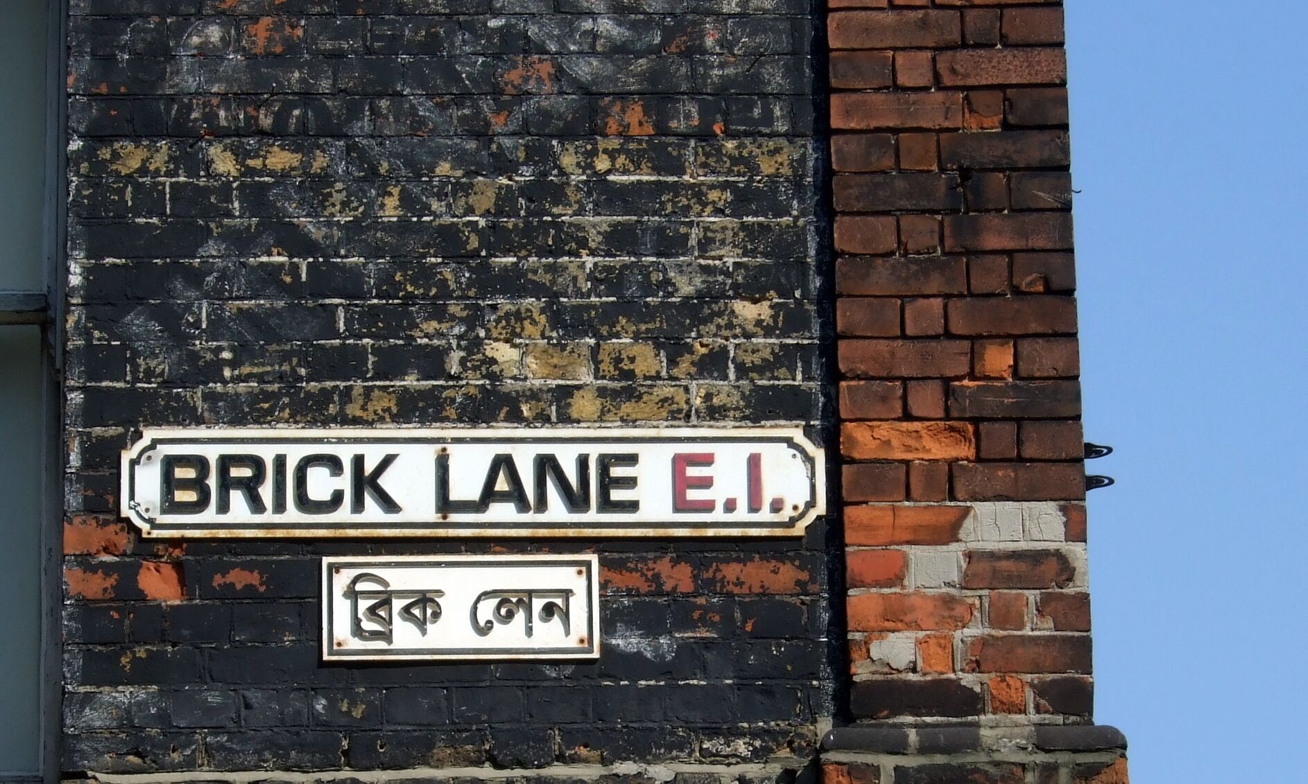 A sign reading "BRICK LANE E.I." with a smaller sign below it in a different script.
