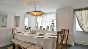 A dining room with a table set for four, wooden chairs, a bench, and a hanging light fixture.