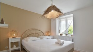 A bedroom with a bed, bedside lamps, a window with curtains, and a view of greenery outside.