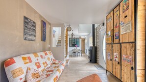 Ein gemütlicher Wohnbereich mit einem gemusterten Sofa, einem Holztisch und einer Wand mit Hinweisschildern.