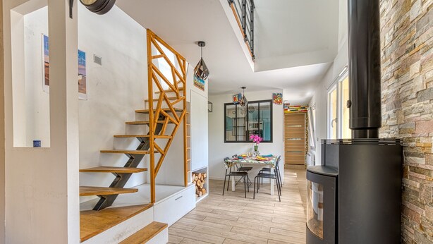Eine moderne Küche mit einem schwarzen Kühlschrank, einer Holztreppe und einem Essbereich mit Tisch und Stühlen.