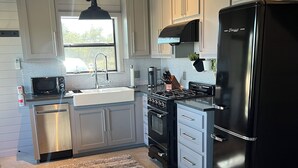 Une cuisine moderne avec des meubles gris, un réfrigérateur noir, une cuisinière et un four à micro-ondes.
