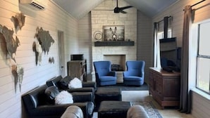 Un salon chaleureux avec une cheminée, des canapés en cuir et un ventilateur de plafond.