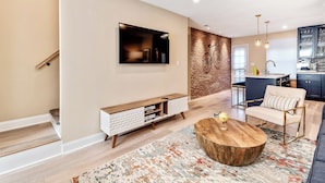 A modern living room with a flat-screen TV, a wooden coffee table, and a patterned rug. - Modern Downtown Retreat 5BR-5Baths (Philadelphia)