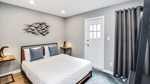 A bedroom with a bed, bedside table, lamp, and a decorative wall piece. - Modern Downtown Retreat 5BR-5Baths (Philadelphia)