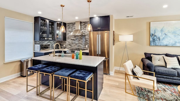 A modern kitchen with a central island, bar stools, and stainless steel appliances. - Modern Downtown Retreat 5BR-5Baths (Philadelphia)