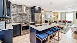 A modern kitchen with a central island, stainless steel appliances, and a brick backsplash. - Modern Downtown Retreat 5BR-5Baths (Philadelphia)
