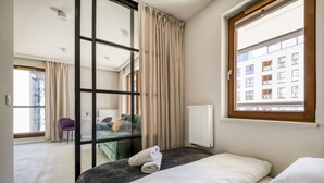Una habitación de hotel moderna con un ventanal amplio, una cama, una silla y vistas a la ciudad.