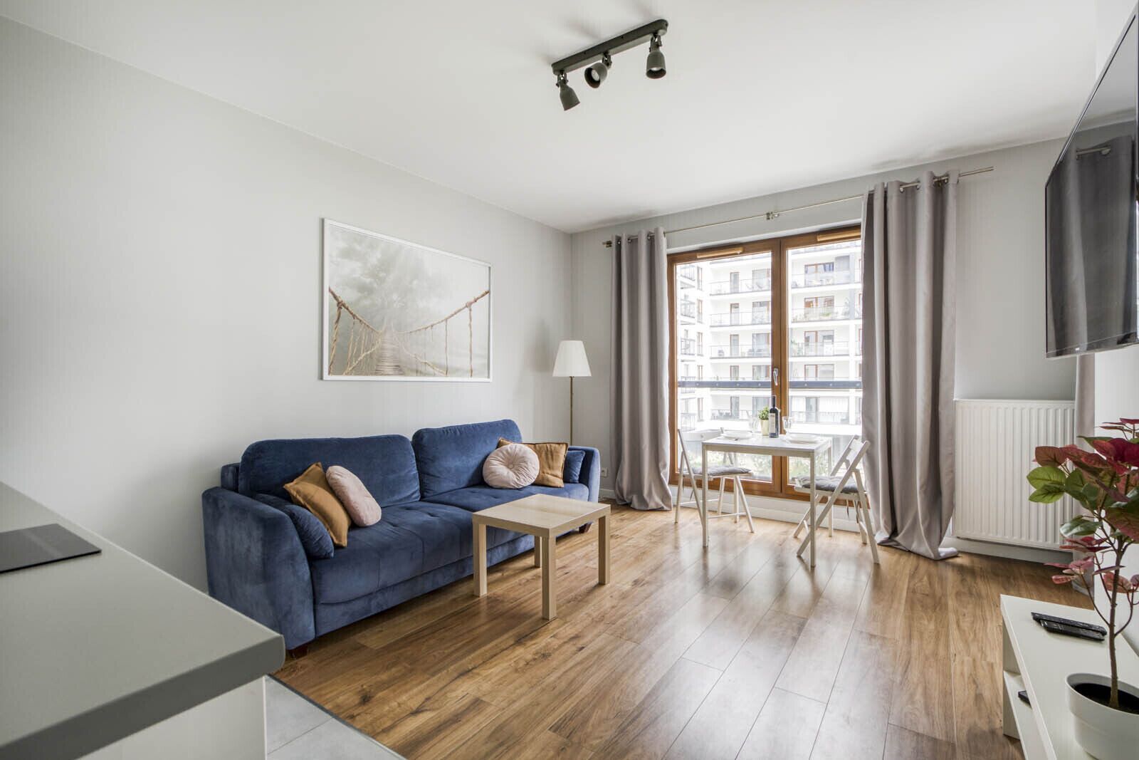 Una sala moderna con un sofá azul, una mesa de centro y un comedor con mesa y sillas.