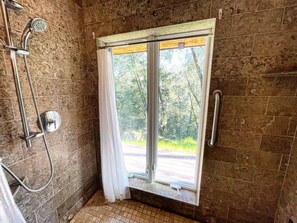 A bathroom with a shower, a window, and a view of the outdoors. - Forest Getaway Cozy, Inviting Cabin w Deck (Inverness)