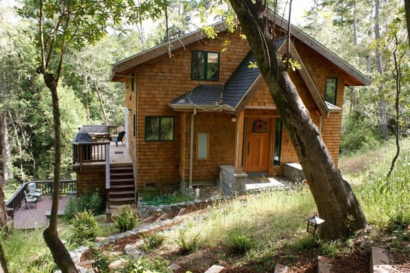 Une cabane en bois dotée d’une terrasse, entourée d’arbres.