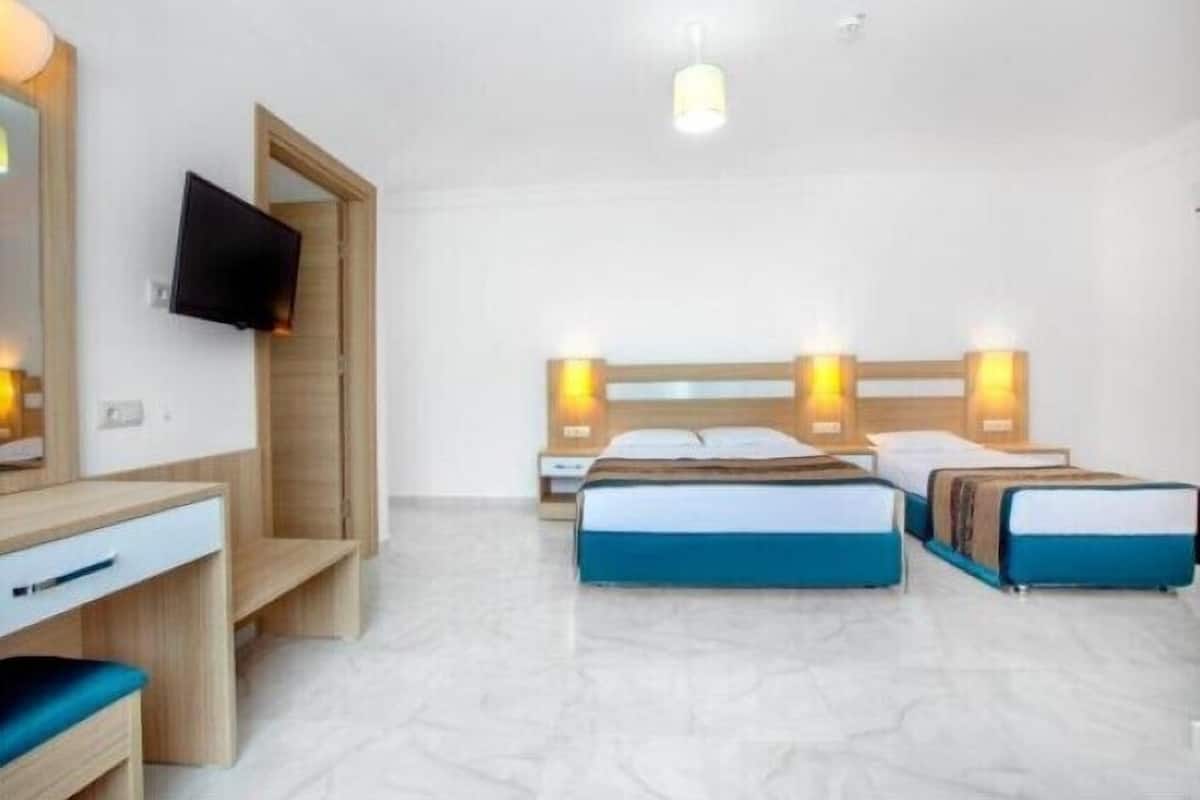 Ein Hotelzimmer mit zwei Betten, einem Schreibtisch, einem Fernseher und einem Spiegel.