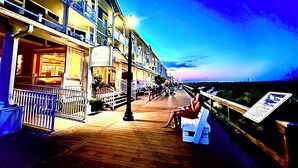 Una pasarela de madera con un banco, un letrero y un edificio con varios balcones y un cartel que dice 'Ocean Suites'.