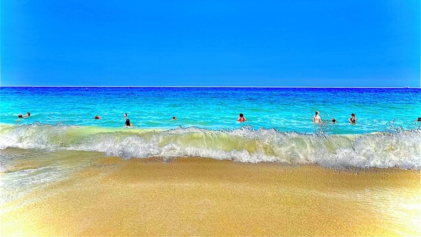 Una playa con aguas azules cristalinas y una orilla arenosa.