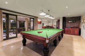 A pool table in a well-lit room with a large window and sliding glass door. - Pezula Lake House (Knysna)