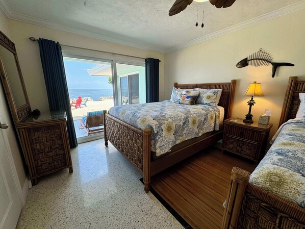 Une chambre d’hôtel avec un lit, une table de chevet, une lampe, un miroir et une vue sur la plage.