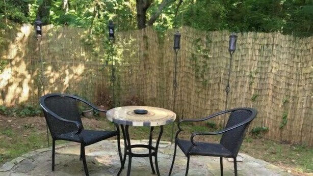 A stone patio with a round table and two chairs.