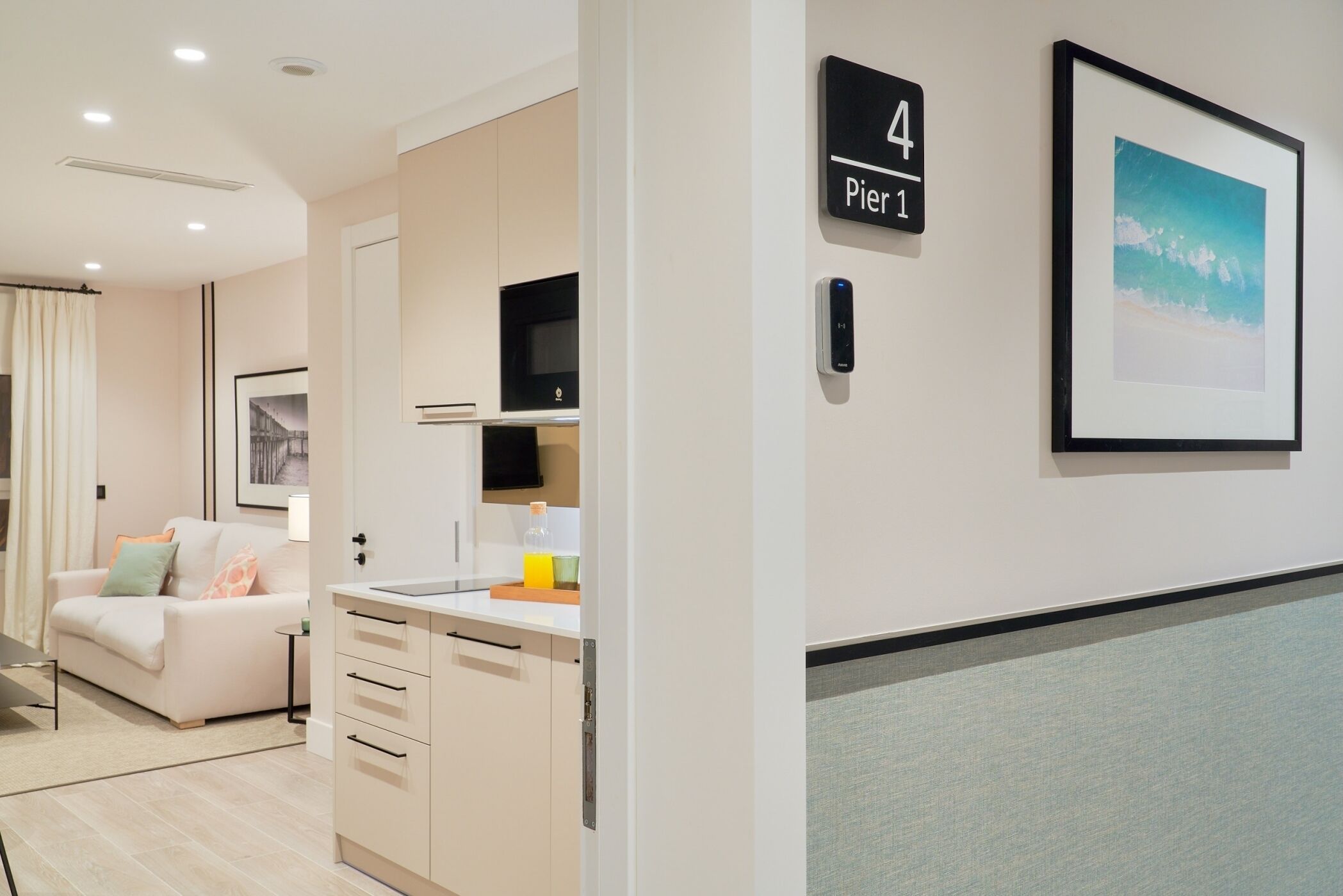 A modern hotel room with a kitchenette, a sofa, a framed picture, and a sign indicating room number 4.