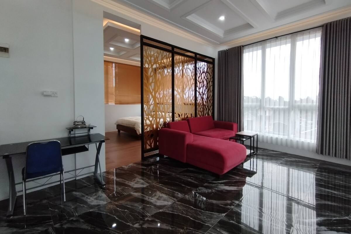 Een moderne hotelkamer met een rode bank, een bureau met stoel, een decoratieve ruimteverdeling en een groot raam met uitzicht.