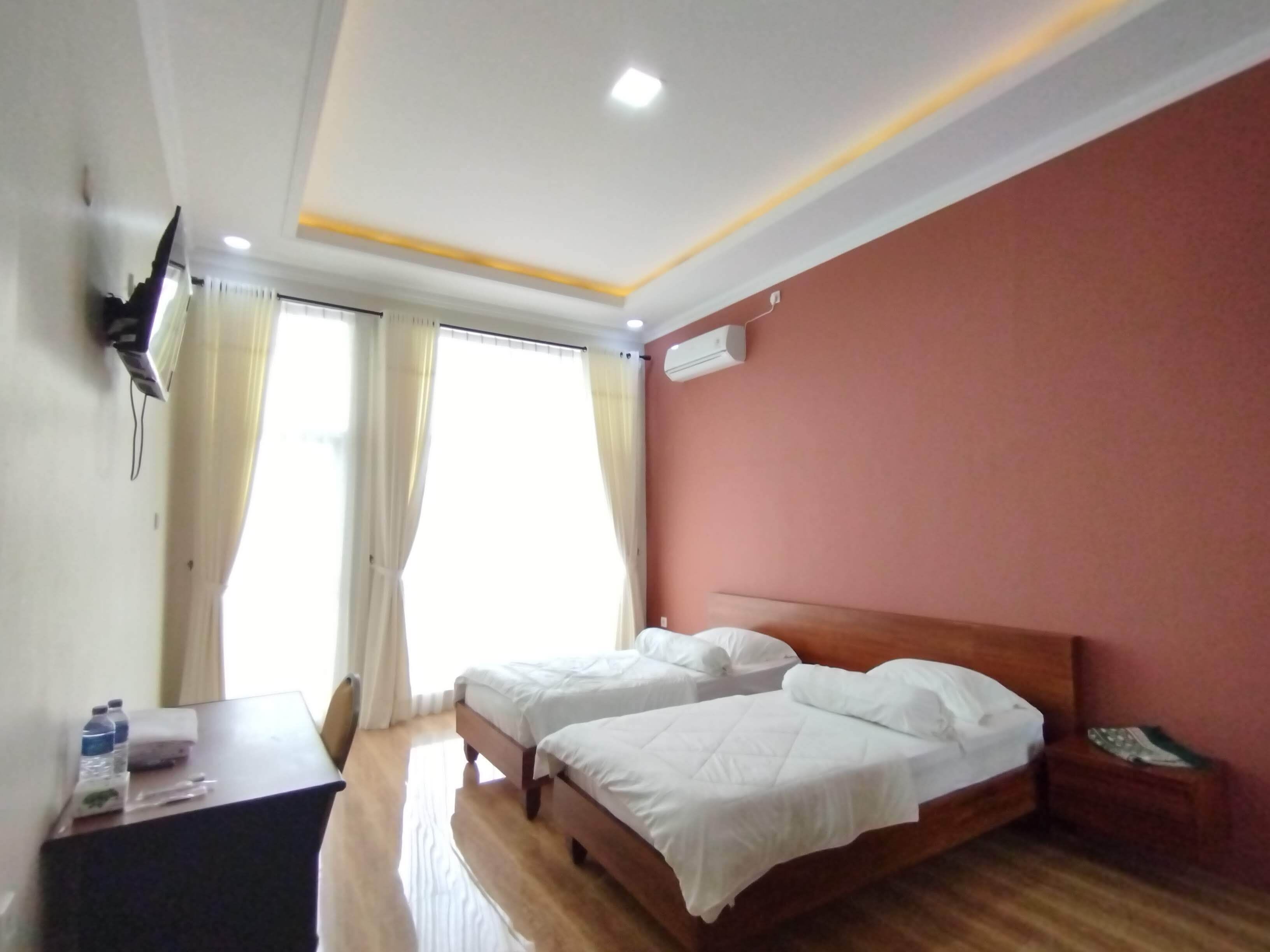 A hotel room with two beds, a desk, and a chair.