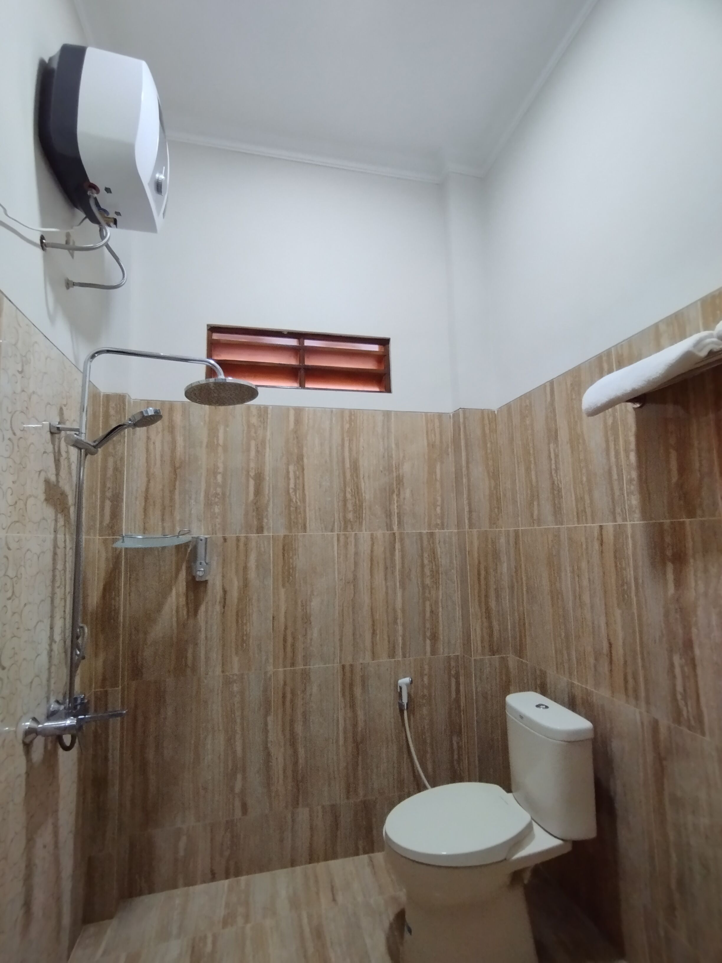 A compact bathroom with a shower, toilet, and a towel rack.