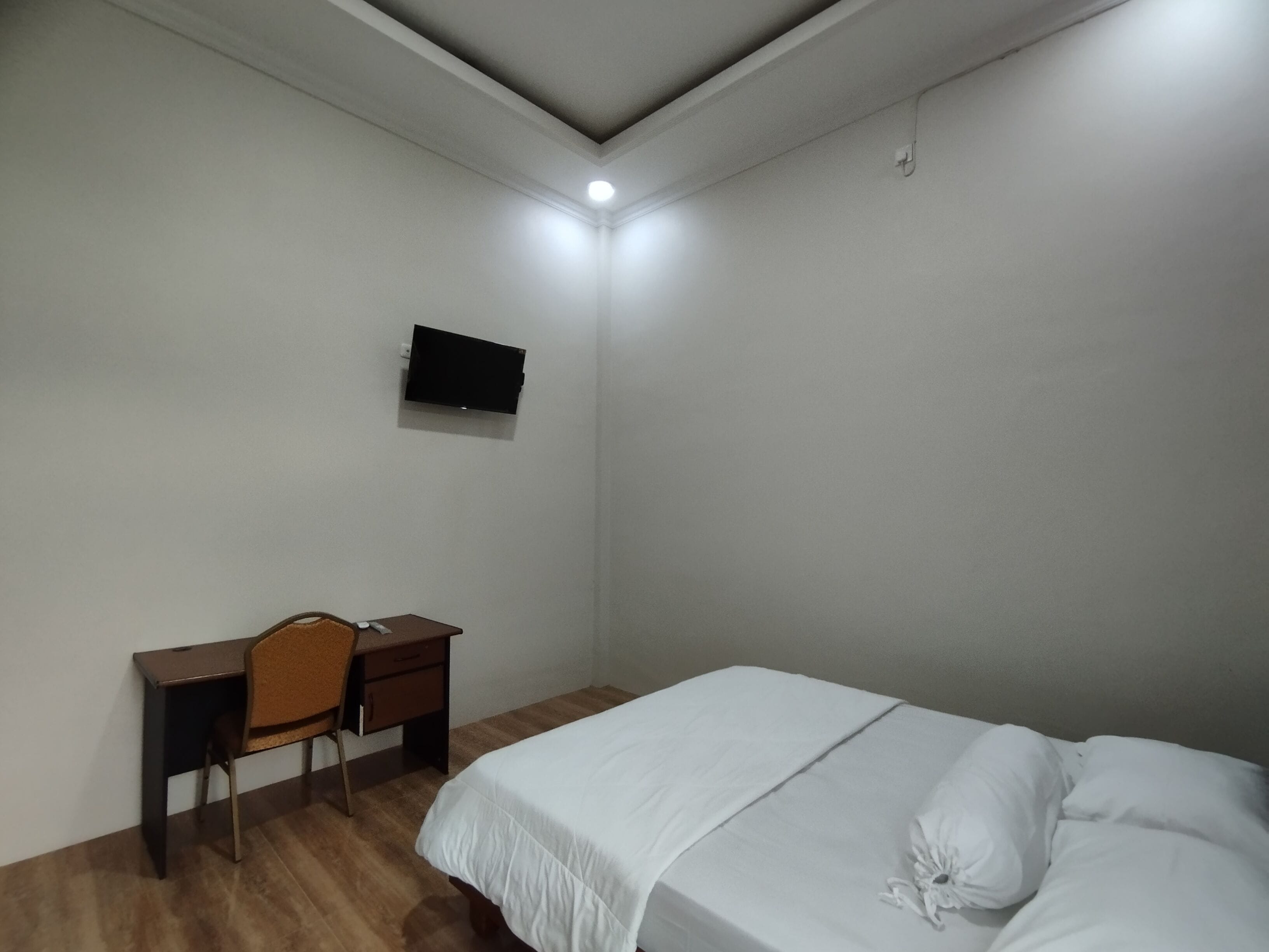 A bedroom with a bed, a desk, and a chair.