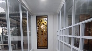 Un escalier étroit avec une rampe noire, des murs blancs et un panneau décoratif orné de motifs géométriques.