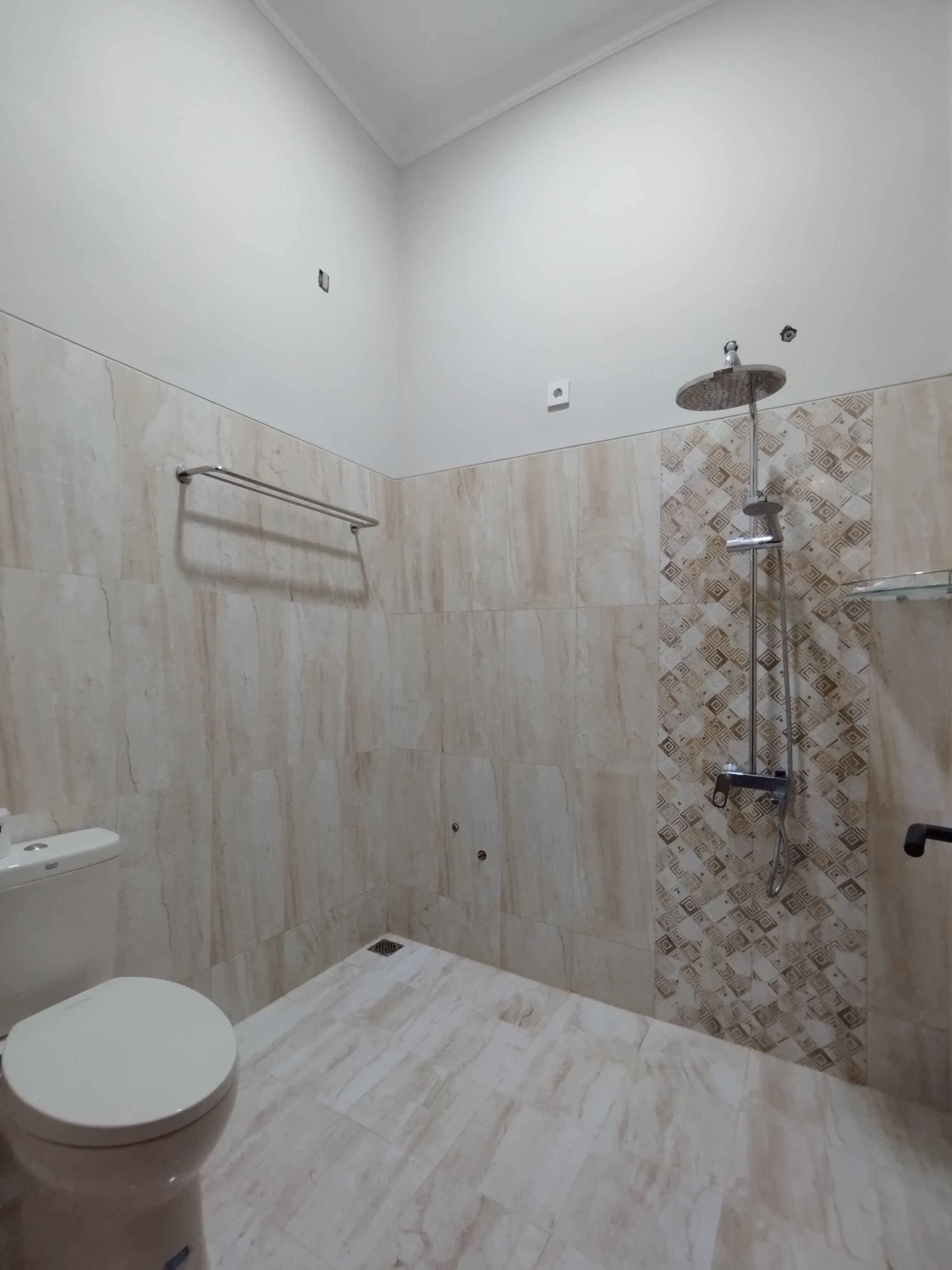 Een badkamer met douche, toilet en handdoekhouder.