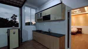 Une cuisine compacte avec des meubles en bois, un four à micro-ondes encastré et un évier.