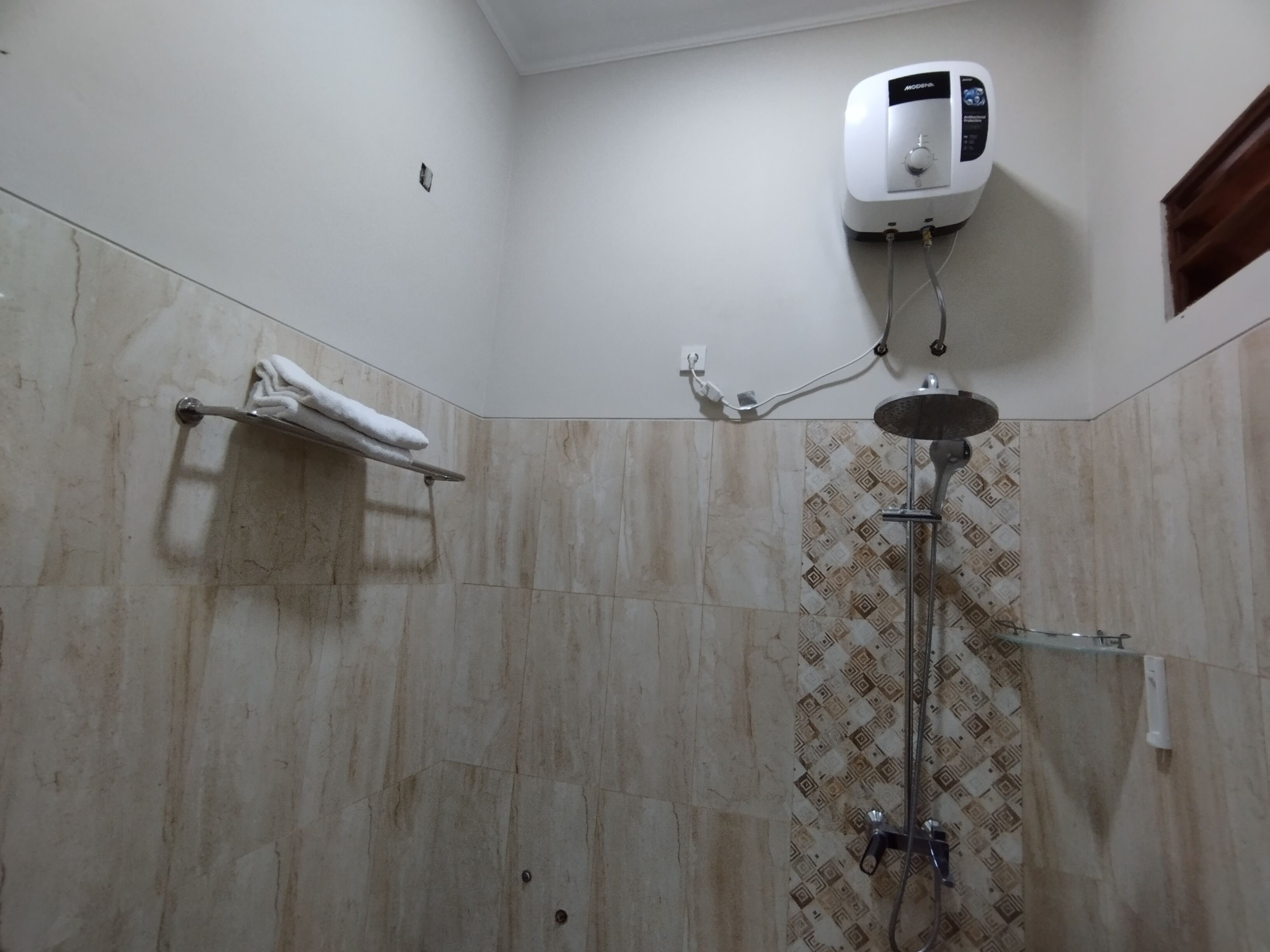 Un baño con ducha, toallero y calentador de agua instalado en la pared.