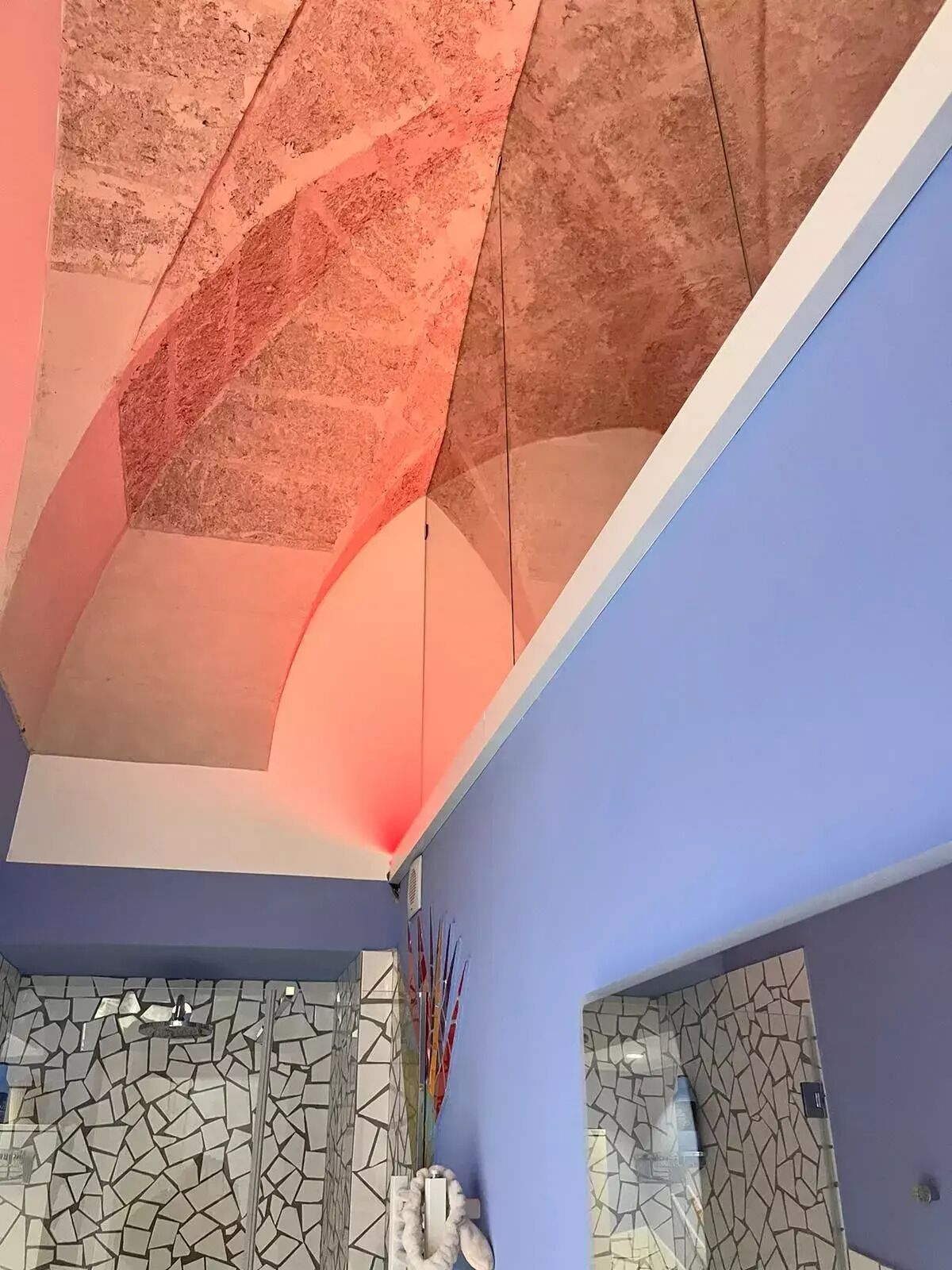 A modern interior with a geometric ceiling design, a blue wall, and a mosaic tile wall.