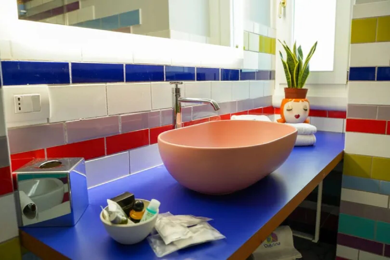 A bathroom with a large pink sink, a mirror, and a blue countertop.