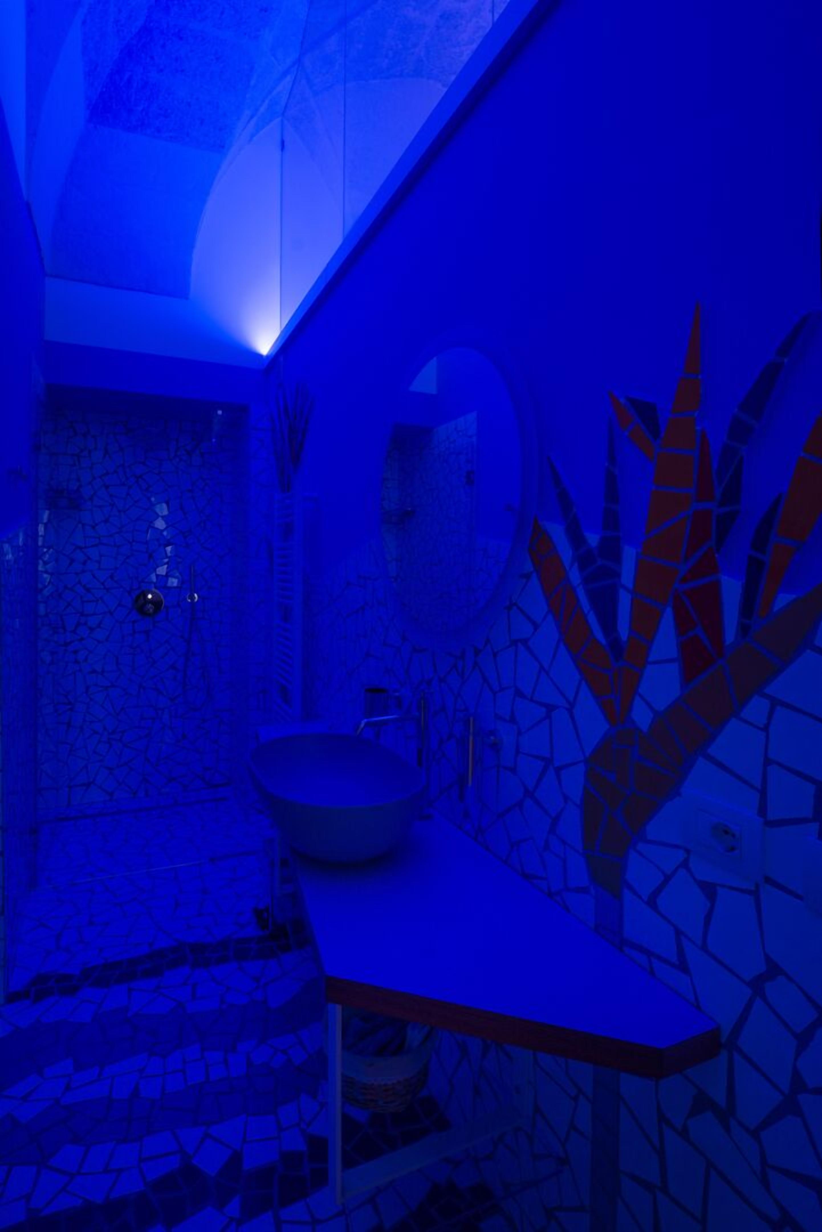 A bathroom with a mosaic tile wall, a sink, and a mirror.