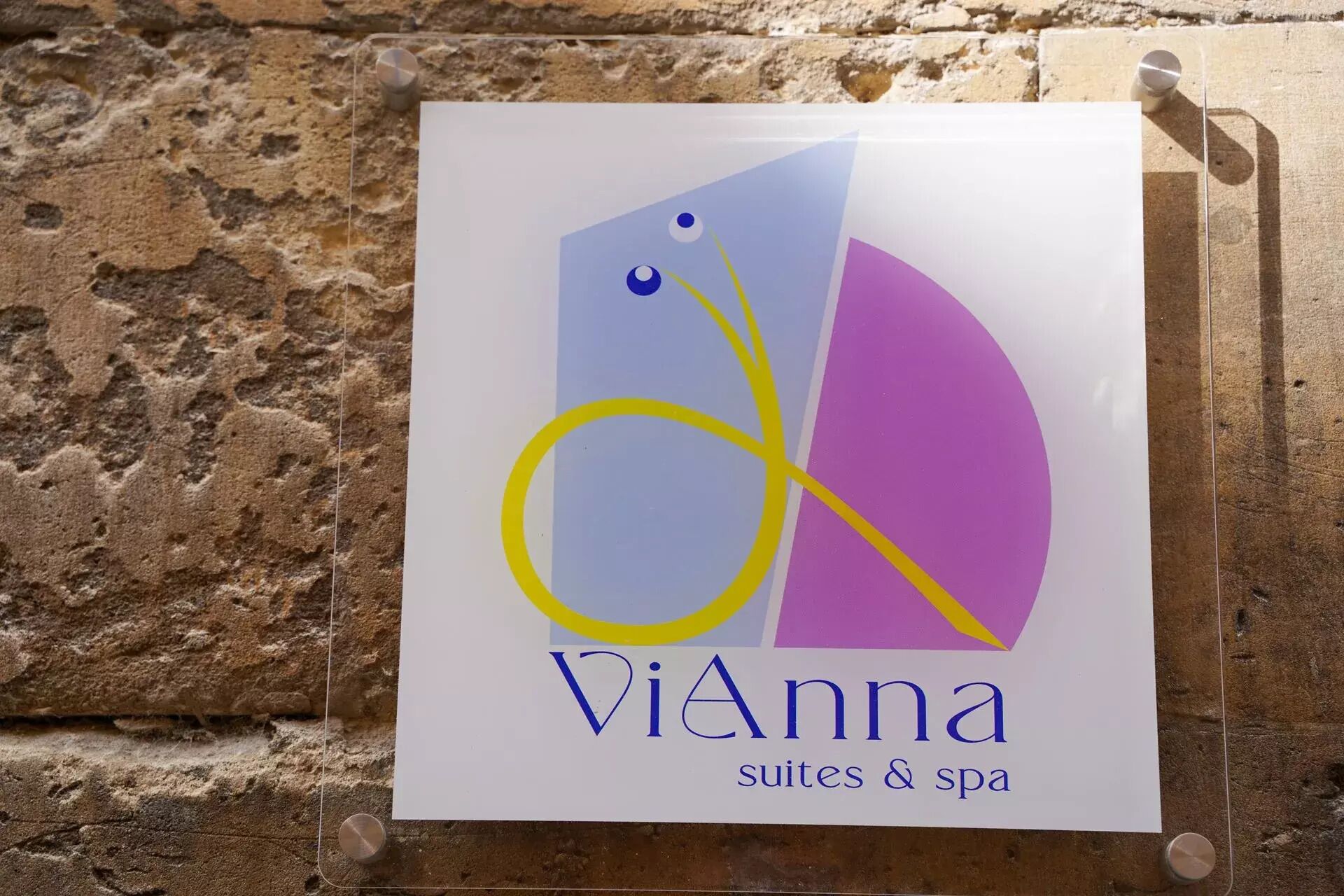 Segnaletica per 'Vianna suites & spa' con un logo raffigurante forme astratte e una 'V' stilizzata.