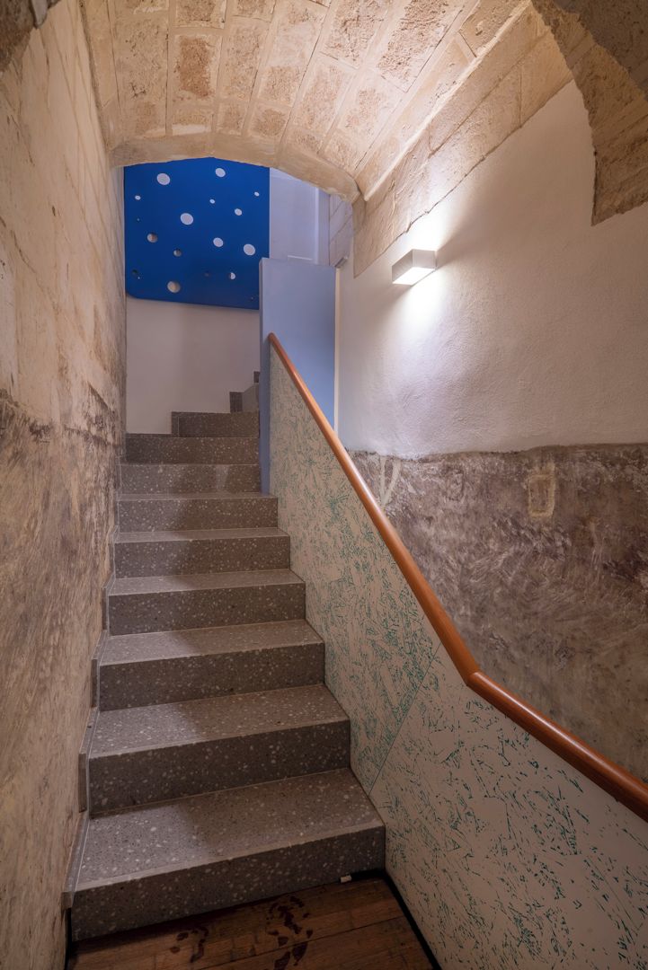 A stone staircase with a handrail, leading to a room with a blue ceiling.