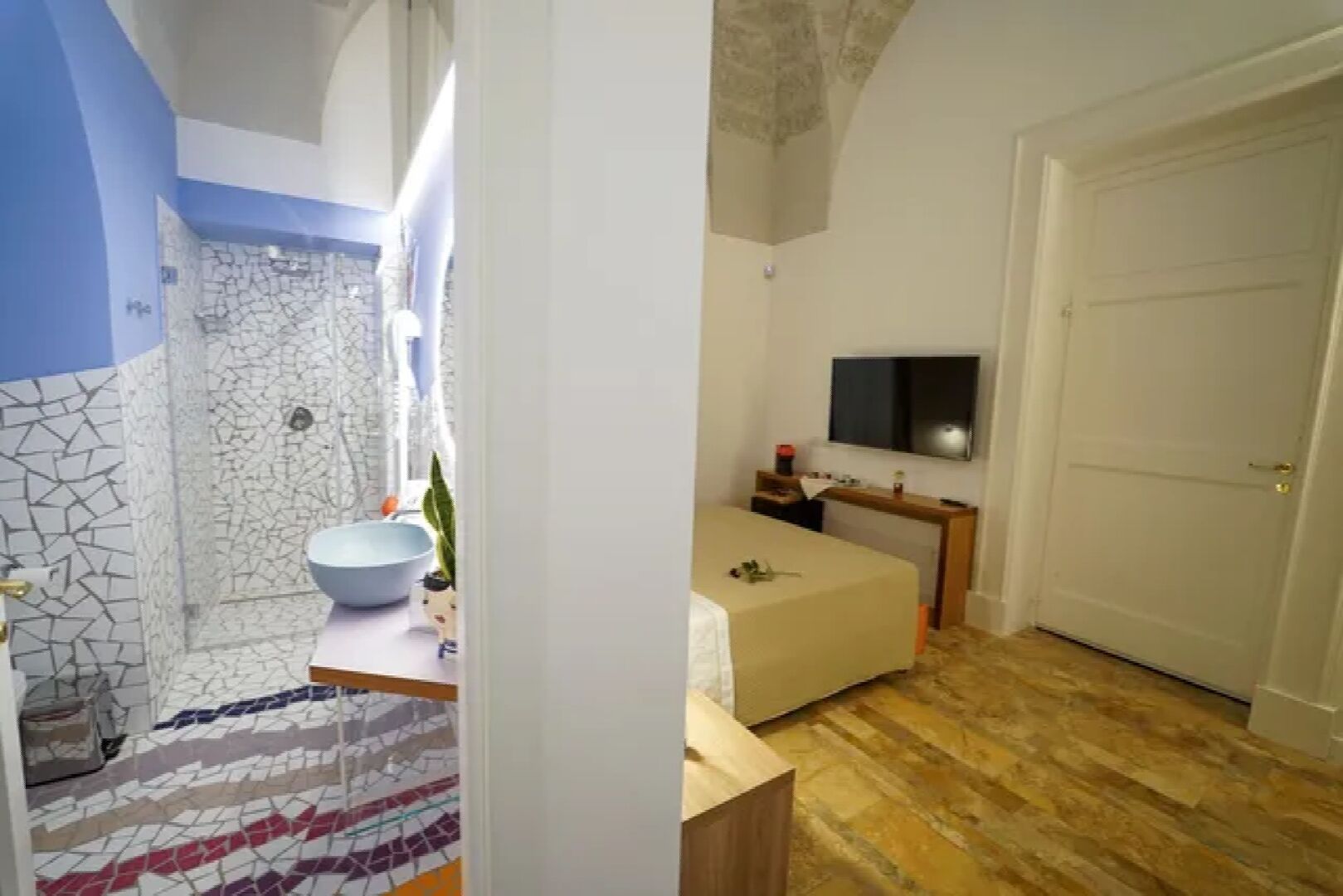 Un baño con ducha de mosaicos y lavamanos de porcelana azul.